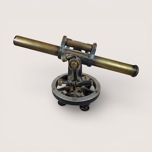 May include: An antique brass and black theodolite, a surveying instrument, with a horizontal telescope and a circular base. The theodolite has a vintage aesthetic, with signs of wear and age, suggesting it is a historical piece.