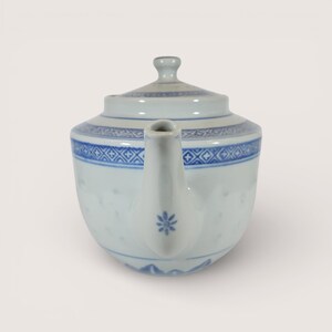 May include: A white porcelain teapot with a lid, featuring blue floral and geometric patterns. The spout has a small blue flower design. The teapot is a traditional shape, suitable for serving tea.