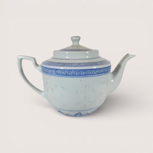 May include: White porcelain teapot with blue geometric patterns around the rim and lid. The teapot has a curved spout and handle, and a small knob on the lid. The body of the teapot has small, evenly spaced holes.