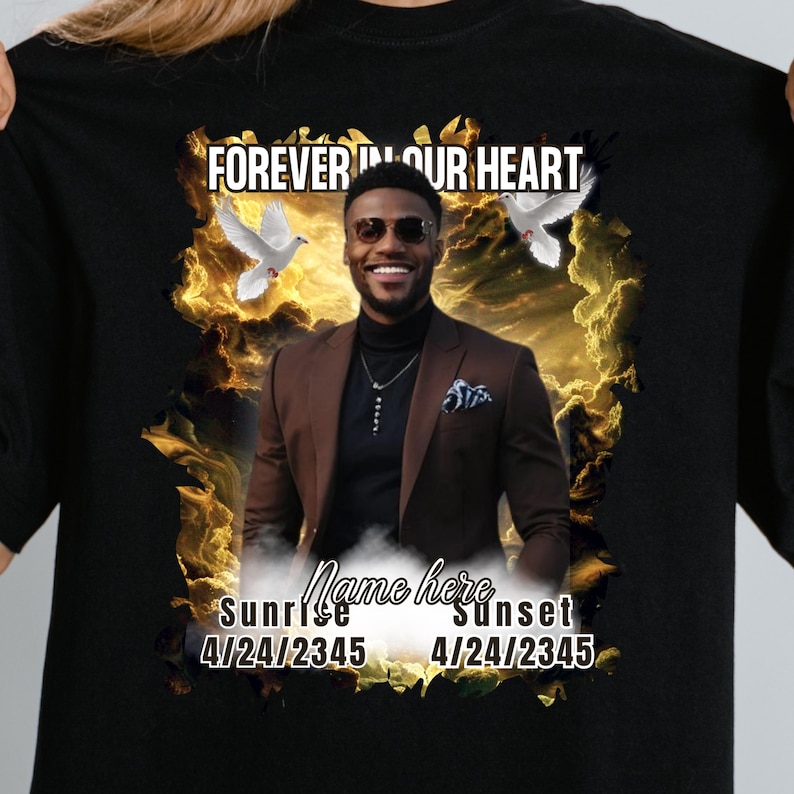 May include: Black t-shirt with a memorial design. The design includes the text "FOREVER IN OUR HEART", a photo of a smiling person, doves, and the words "Sunrise" and "Sunset" with dates.