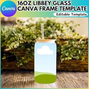 Puede incluir: Un vaso de vidrio Libbey de 473 ml con tapa de bambú y una pajita. El vaso tiene un diseño azul y verde con una nube blanca sobre un fondo azul. El vaso está sobre una superficie de madera.
