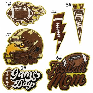 Op de afbeelding: Een verzameling geborduurde patches met een American football thema. Ontwerpen omvatten een voetbal met vlammen, een footballhelm met een adelaar, de woorden "Game Day", een bliksemflits voetbal, een wimpel met "Football" en de woorden "Football Mom".