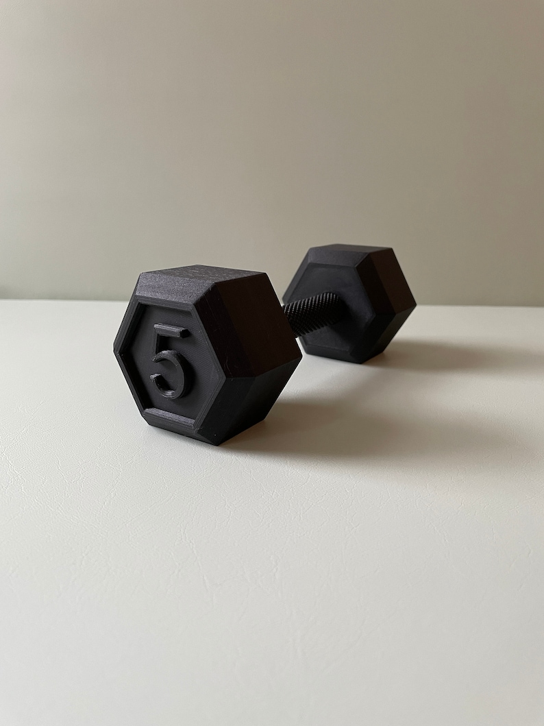 May include: A black 5-pound dumbbell with a hexagonal shape.