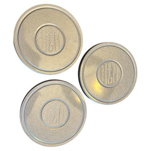 Puede incluir: Tres botes de película de metal plateado con el texto "Kodak" y "Professional" impreso en las tapas.