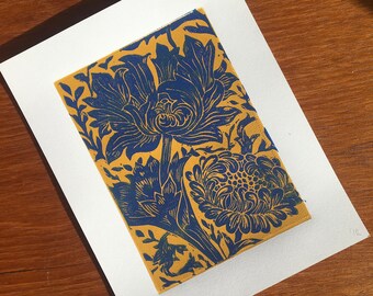 May include: A blue and gold floral print on a white background. The print features a large flower with intricate details and smaller flowers surrounding it.