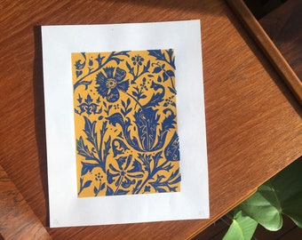 May include: A blue and yellow floral print on a white background. The print features a repeating pattern of stylized flowers and leaves.