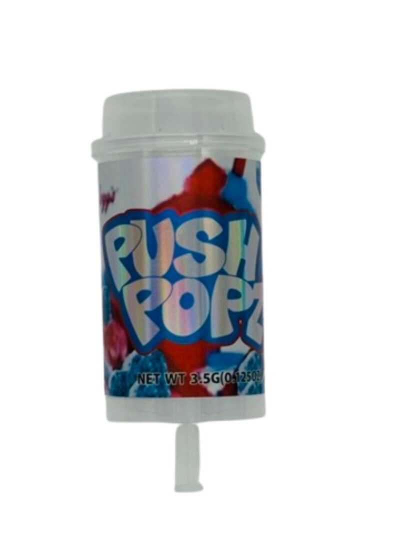 May include: A Push Popz candy container with a white cap and a push-up stick. The container has a silver background with red and blue abstract designs. The words "PUSH POPZ" are in large, blue, bubble letters.