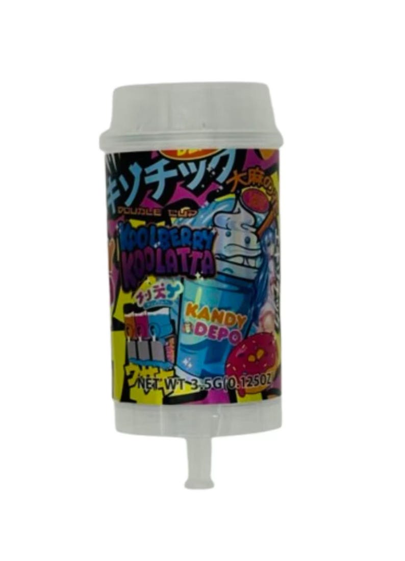May include: A cylindrical candy container with a white lid. The label features Japanese text, a cartoon character, and the words "Blueberry Koolatta" and "Kandy Depo". The net weight is 3.5g (0.125oz).