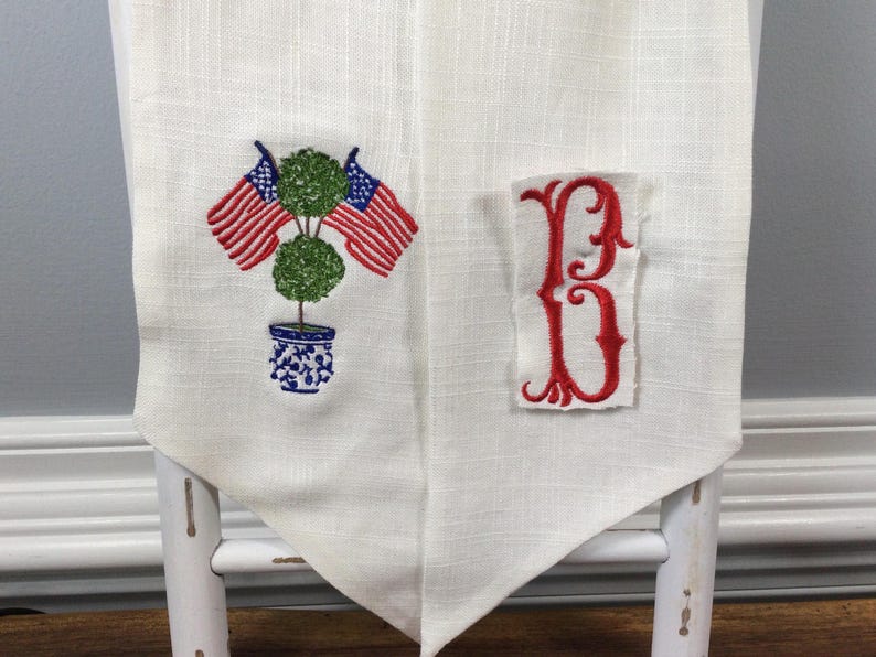 Personalized embroidered wreath sash with American flag on a green topiary, chinoiserie vase with topiary, 4th of July personalized decor
