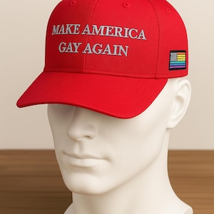 May include: A red baseball cap with the phrase "MAKE AMERICA GAY AGAIN" embroidered in silver. A small rainbow flag patch is on the side. The cap is displayed on a white mannequin head.