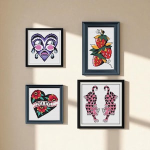 Puede incluir: Cuatro obras de arte en punto de cruz enmarcadas. Las piezas incluyen un corazón llorando, fresas, un corazón con la palabra "MUM" y flores, y dos leopardos rosas con manchas en forma de corazón. Los marcos son negros y azul marino.