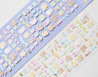 May include: Two sticker sheets with a variety of pastel-colored illustrations. The stickers feature bears, bunnies, carrots, and other cute designs. One sheet is on a light purple background, and the other is on a clear background.