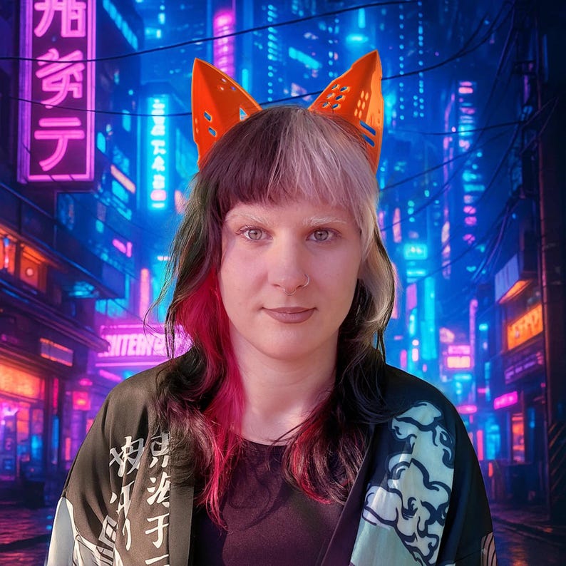 May include: A person wearing orange fox ear headwear, a black shirt, and a black and teal kimono-style jacket. The person has multi-colored hair with black, pink, and white sections. The background features a neon-lit cityscape.