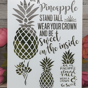 May include: A white stencil with a pineapple theme. The design includes several pineapple illustrations and the text "Be a Pineapple, Stand Tall, Wear Your Crown, and Be Sweet on the Inside." The stencil is suitable for various craft projects.