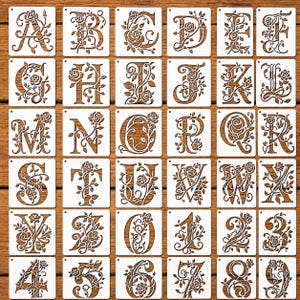Può includere: Una collezione di stencil in legno con lettere e numeri con disegni floreali. Ogni stencil presenta una lettera o un numero diverso, intagliato in modo intricato con rose e viti. Gli stencil sono su sfondo bianco.