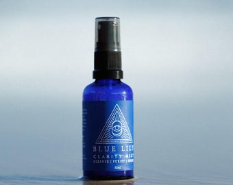 May include: A blue glass bottle with a black spray nozzle. The bottle is labeled "Blue Lily Clarity Mist Cleanse | Purify | Open".