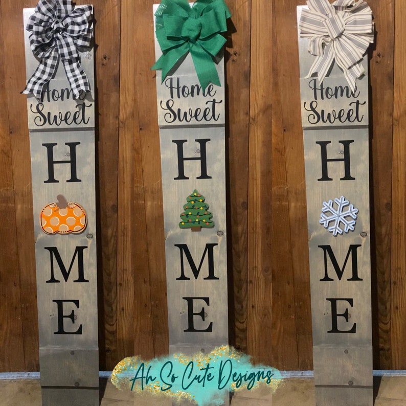 May include: Three wooden signs with the words "Home Sweet Home" spelled vertically. The signs are decorated with a pumpkin, a Christmas tree, and a snowflake.