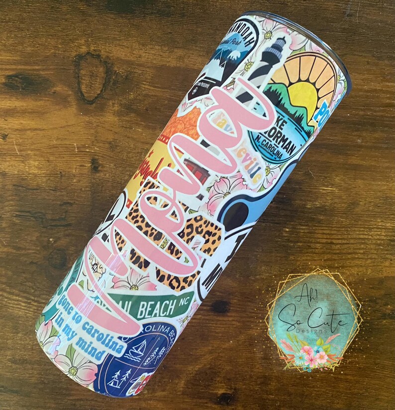 May include: A pink and white tumbler with a variety of colorful stickers, including a lighthouse, a beach scene, and the words "gone to Carolina in my mind".