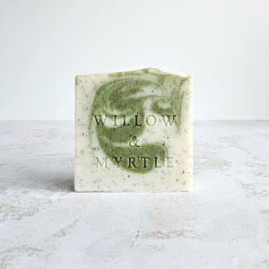 Pode incluir: Uma barra de sabonete com um padrão de redemoinho verde e branco. O sabonete é rotulado como "Willow & Myrtle".