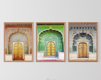 May include: Three framed prints of ornate doorways with intricate tile work and arched entryways. The doorways are all painted in shades of gold, green, and blue. The prints are displayed on a white wall with two brown leather armchairs and a coffee table in front of them.