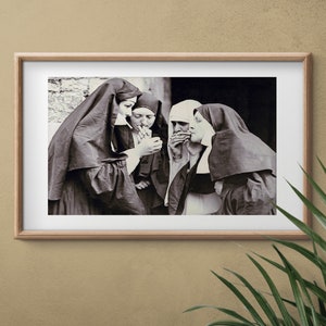 May include: A black and white photograph of four nuns standing together, each holding a cigarette. The nuns are wearing traditional habits, and the photo is framed in a wooden frame.