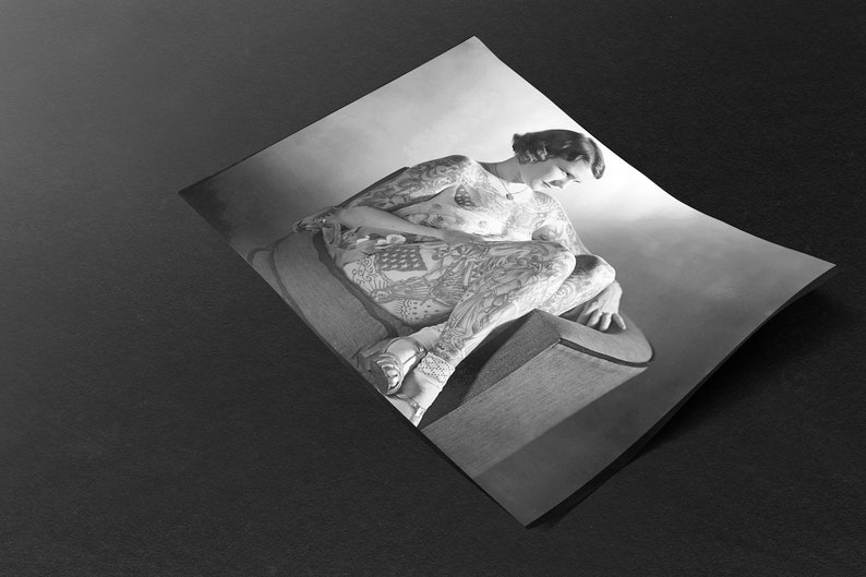 Puede incluir: Una fotograf&iacute;a en blanco y negro de una persona sentada en una silla. La persona est&aacute; cubierta de tatuajes. Los tatuajes son intrincados y detallados, y cubren todo el cuerpo de la persona.