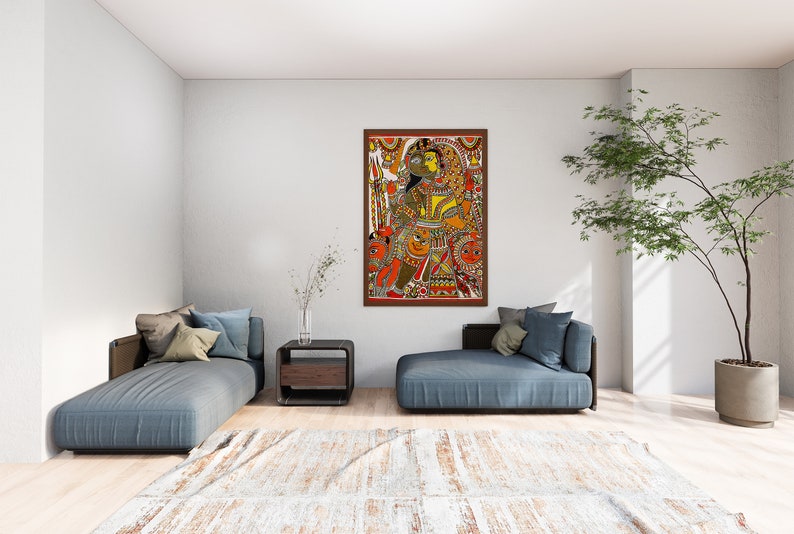 May include: A framed painting of a colorful Indian folk art scene depicting a couple in traditional clothing. The painting is set against a white wall in a modern living room with a blue couch and a potted plant.