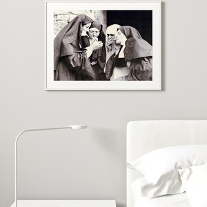 May include: Black and white photograph of four nuns standing together, smoking cigarettes. The nuns are wearing traditional habits and are looking at the camera.