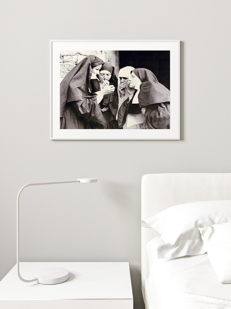 May include: Black and white photograph of four nuns standing together, smoking cigarettes. The nuns are wearing traditional habits and are looking at the camera.
