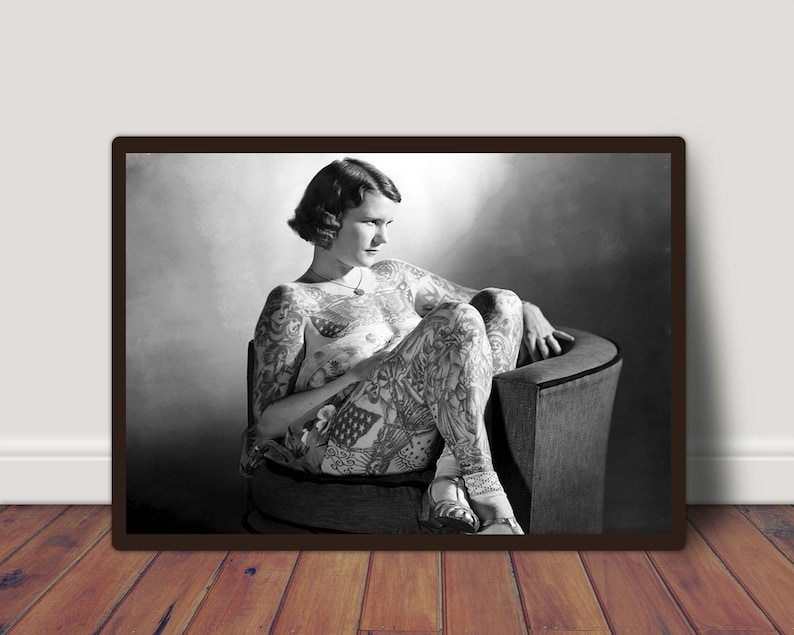 Puede incluir: Una fotograf&iacute;a en blanco y negro de una mujer sentada en una silla. Lleva un atuendo sencillo y tiene un tatuaje en todo el cuerpo.
