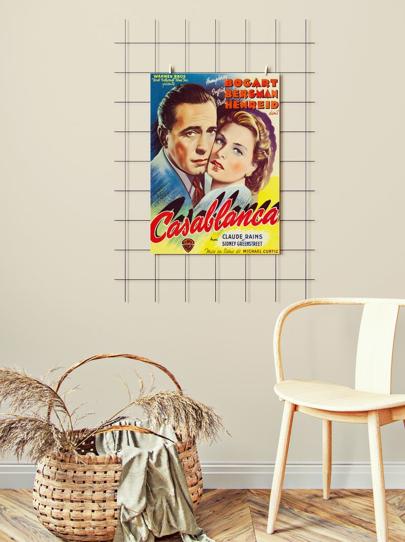 May include: A framed vintage movie poster for "Casablanca" featuring Humphrey Bogart and Ingrid Bergman. The poster has a yellow and red title with the names of the actors and director. The poster is hanging on a grid.