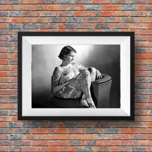 Puede incluir: Una foto en blanco y negro de una mujer sentada en una silla. Lleva un vestido y tiene tatuajes en todo el cuerpo.