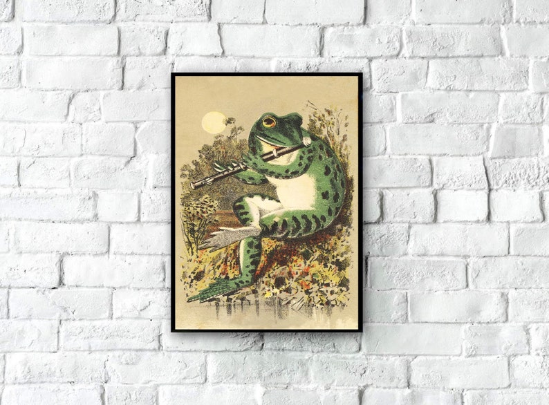 May include: A vintage illustration of a green frog playing a flute in a marshland setting. The frog is sitting on a log and has a large, round eye. The illustration is in a black frame.
