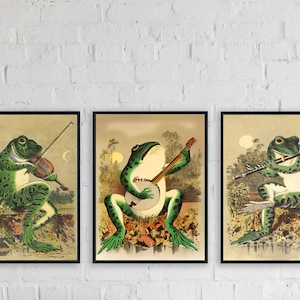 May include: Three framed illustrations of frogs playing musical instruments. The first frog plays a violin, the second plays a banjo, and the third plays a flute. The illustrations are in a vintage style with a light brown background.