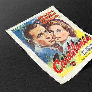May include: A vintage movie poster for the film "Casablanca" featuring Humphrey Bogart and Ingrid Bergman. The poster has a colorful design with the film's title in red and yellow, and the Warner Bros. logo.