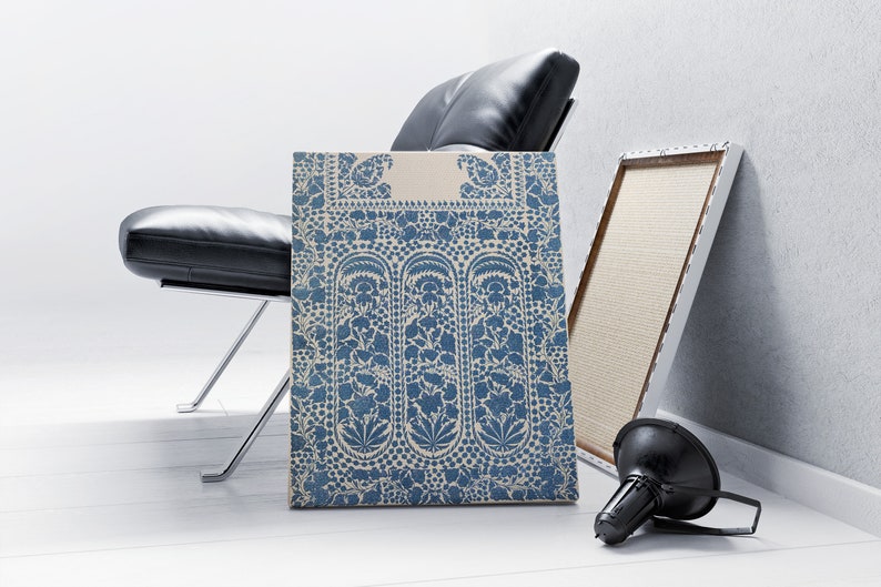 Puede incluir: Una impresi&oacute;n en lienzo con estampado azul y blanco con un dise&ntilde;o floral. La impresi&oacute;n se apoya en una silla de cuero negro y un marco blanco.