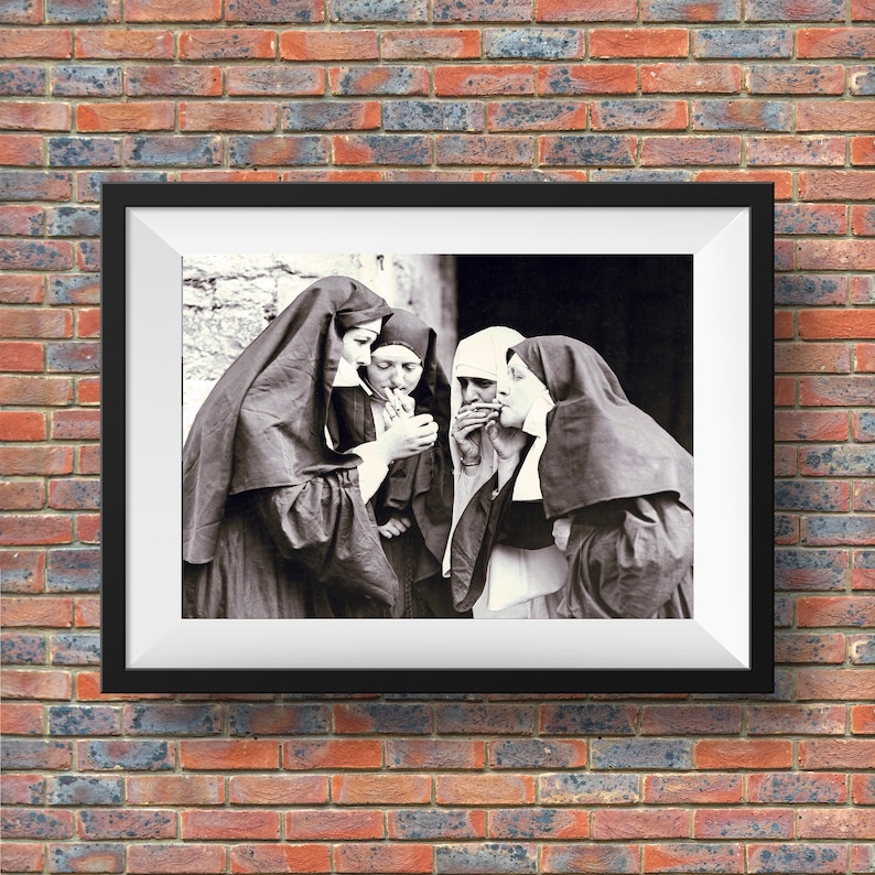 May include: Black and white photograph of four nuns in habits, standing together and smoking cigarettes. The nuns are looking at the camera.