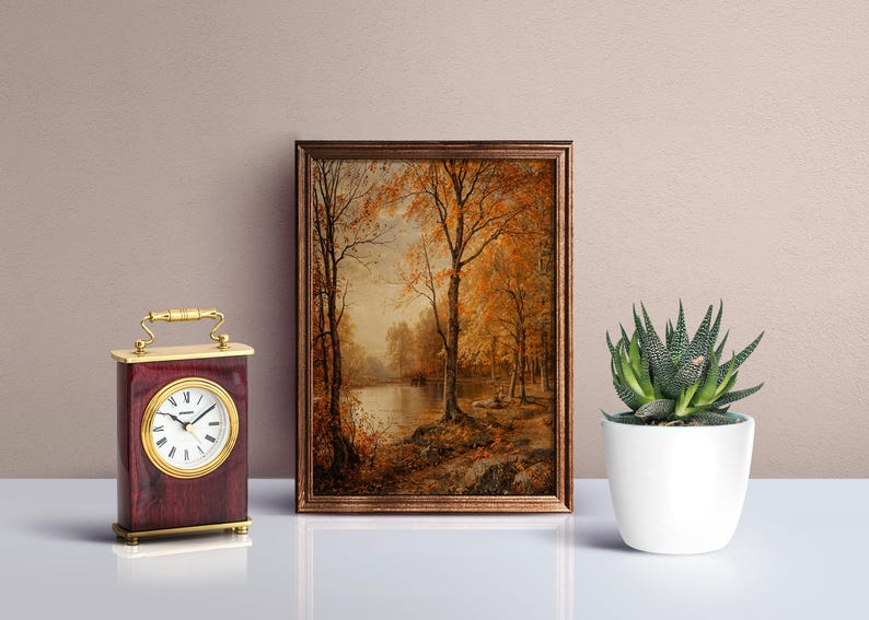 May include: A framed painting of a forest scene with a lake in the background. The trees are in autumn colors of yellow, orange, and red. The lake is calm and reflective. The painting is in a brown frame.