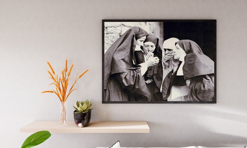 May include: Black and white photograph of four nuns in habits, standing together and smoking cigarettes.