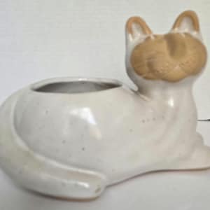 May include: White ceramic cat planter with a brown face and ears. The planter has a round opening for planting.