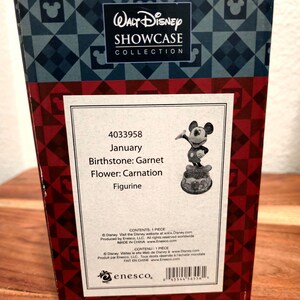 May include: A box from the Walt Disney Showcase Collection. The box is red and black with a Mickey Mouse figurine. The box has the text "January, Birthstone: Garnet, Flower: Carnation, Figurine."