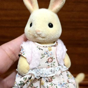 Op de afbeelding: Een set van drie keramische mokken met een gespikkelde, cr&egrave;mekleurige glazuur. Elke mok heeft een ander handgeschilderd ontwerp: een blauw en groen blad, een gele bloem en een rode bes. De mokken hebben een eenvoudige, afgeronde vorm.