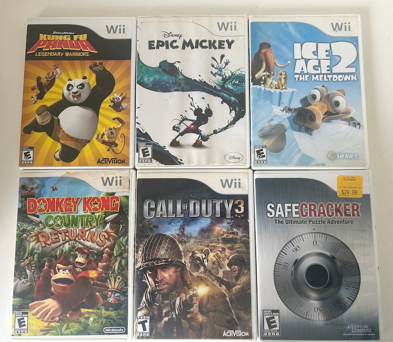 K&ouml;nnte beinhalten: Sechs Wii-Spiele werden gezeigt. Zu den Titeln geh&ouml;ren "Kung Fu Panda", "Epic Mickey", "Ice Age 2", "Donkey Kong Country Returns", "Call of Duty 3" und "SafeCracker". Die H&uuml;llen zeigen farbenfrohe Grafiken und Spiellogos.