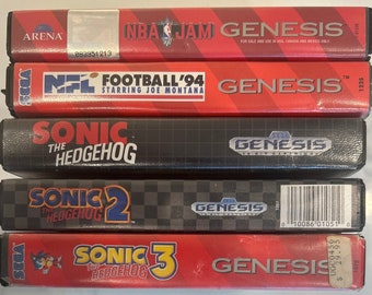 May include: A stack of five Sega Genesis video game cartridges. The cartridges are for the games NBA Jam, NFL Football '94, Sonic the Hedgehog, Sonic the Hedgehog 2, and Sonic the Hedgehog 3. The cartridges are all in their original packaging.