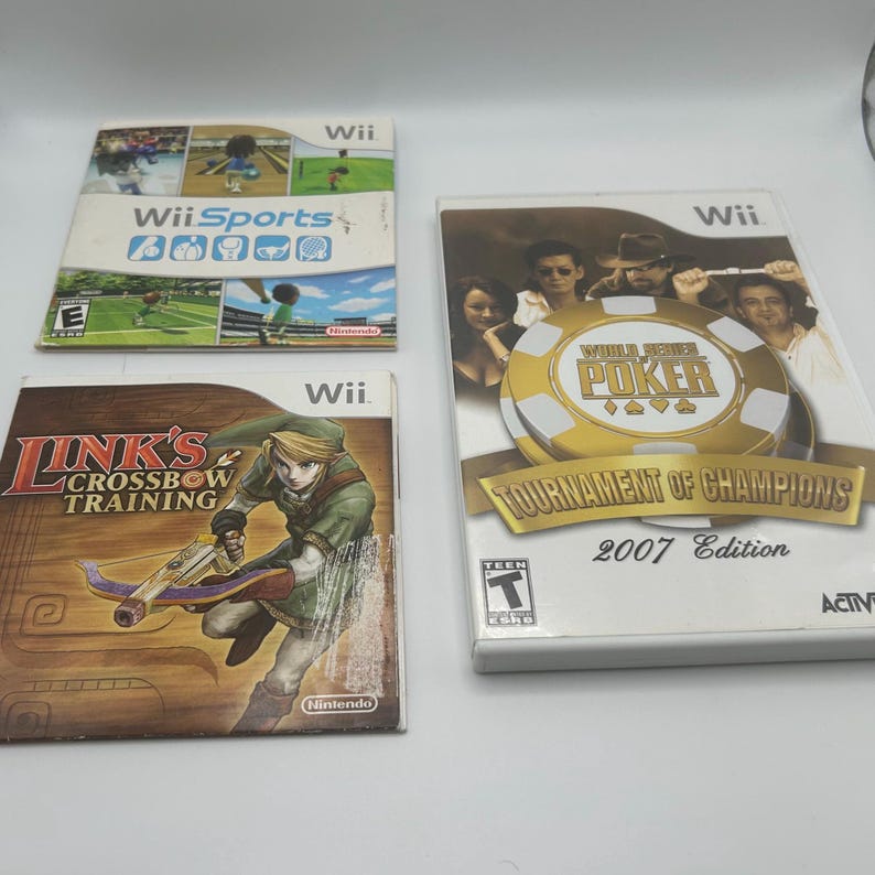 K&ouml;nnte beinhalten: Drei Wii-Videospielh&uuml;llen. Die obere H&uuml;lle ist "Wii Sports" mit verschiedenen Sportfiguren. Die mittlere H&uuml;lle ist "Link's Crossbow Training" mit einer Figur, die eine Armbrust h&auml;lt. Die untere H&uuml;lle ist "World Series of Poker: Tournament of Champions 2007 Edition".