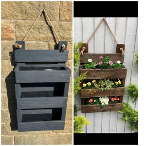 May include: A three-tiered wooden planter with a dark grey stain. The planter is hanging from a wall with twine. The planter is empty in the first image and filled with plants in the second image.