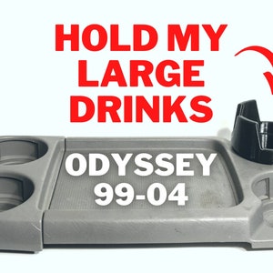 May include: Gray plastic tray with two cup holders and a larger cup holder for larger drinks. The tray has the text "HOLD MY LARGE DRINKS" and "ODYSSEY 99-04" printed on it.