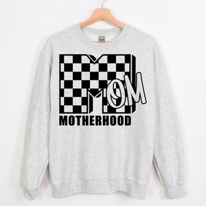 May include: A gray sweatshirt with a black and white checkered design and the word "MOM" in a black and white checkered design. The text "MOTHERHOOD" is printed below the design.