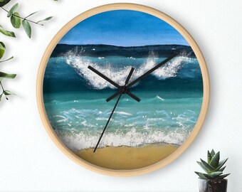 May include: A round wooden clock with a painted image of a blue ocean wave crashing on a sandy beach. The clock face has black hands and a white background.