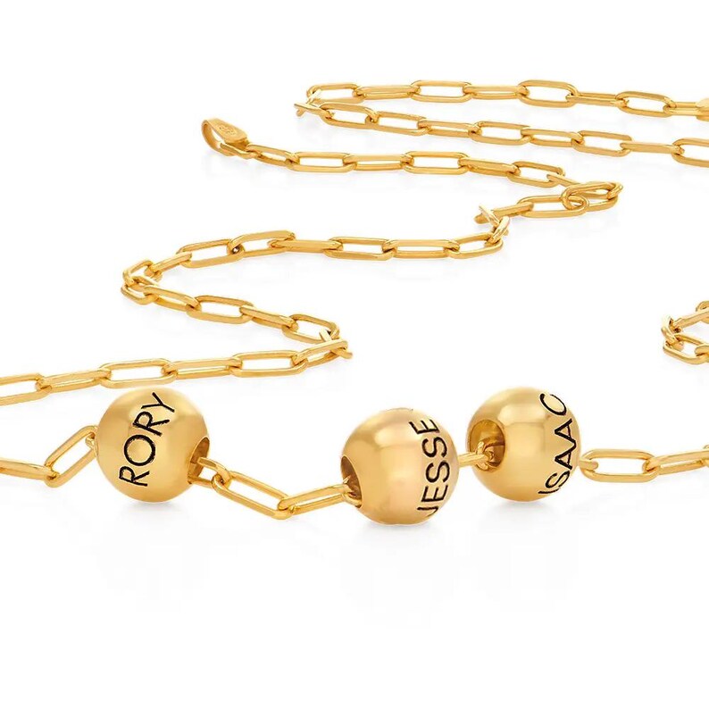 K&ouml;nnte beinhalten: Goldkette mit drei runden Perlen, jede mit einem Namen graviert: Rory, Jesse und Isaac.